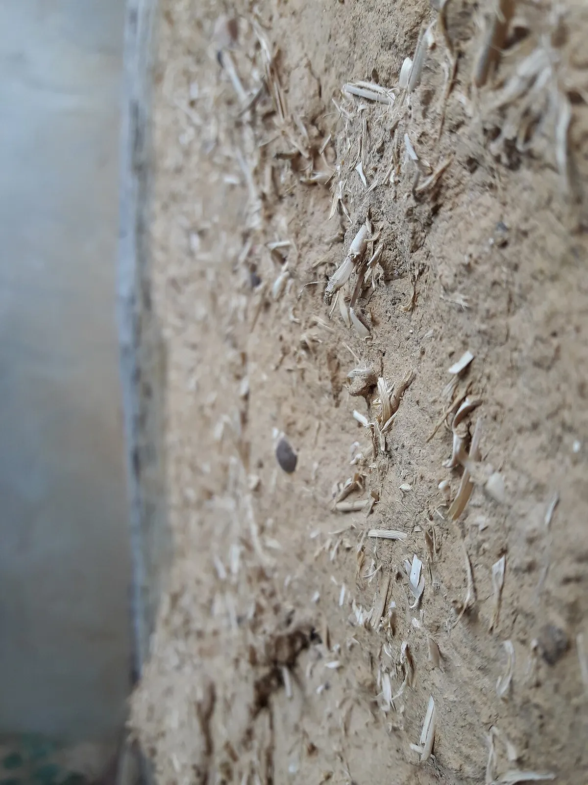Close up of an adobe wall surface with straw mixed into the mud