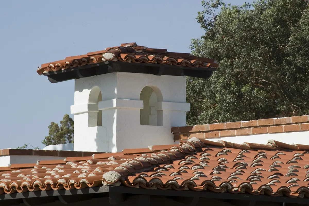 White stucco chimney with arched openings on a clay tile roof